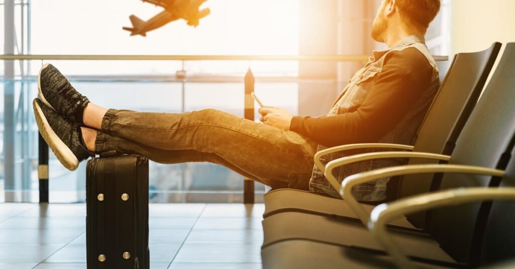 Traveler relaxes at airport while waiting for flight boarding, with plane taking off in background.