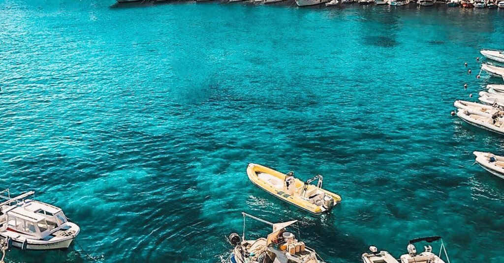 Boats in the vibrant blue waters of Hvar, Croatia, showcasing a charming coastal town under sunny skies.